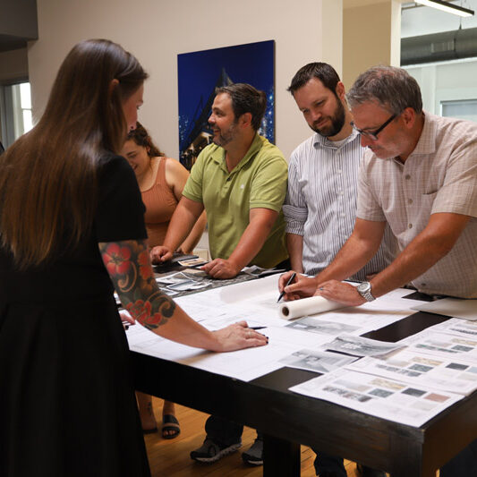 people standing around architectural drawings